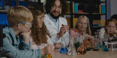 Students in a science class watch a chemistry experiment with colorful liquids.