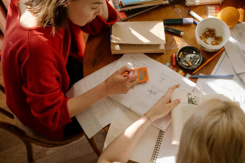Two students engaged in studying at a table with textbooks, notes, and stationery.
